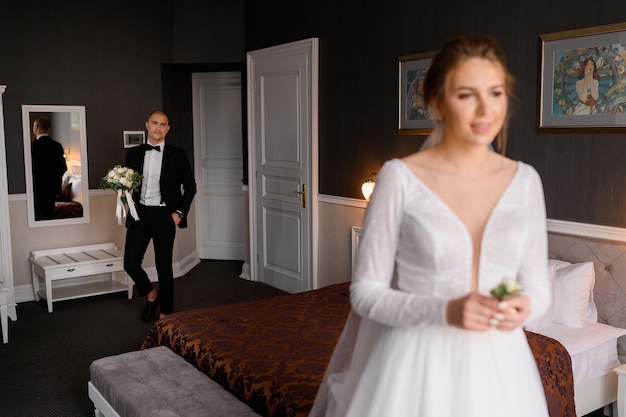 Foto gratuita desenfoque de una novia atractiva con un vestido elegante que sostiene el ojal de la boda y espera reunirse con su novio en el apartamento del hotel mientras