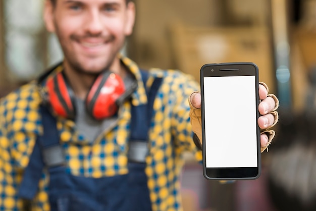 Foto gratuita desenfoque del retrato de un carpintero masculino que muestra su teléfono inteligente con pantalla blanca