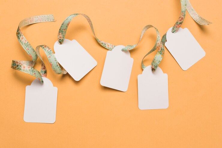Photo Gratis designer ribbon through empty labels arranged on bright yellow surface