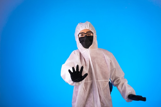 Desinfectante en uniforme preventivo especial y máscaras negras hace señales de alto.