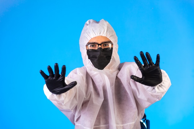 Desinfectante en uniforme preventivo especial y máscaras negras hace señales de alto.