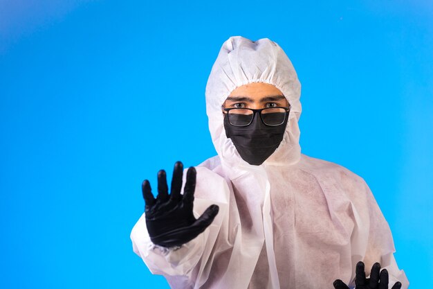 Desinfectante en uniforme preventivo especial y mascarillas detiene el peligro con una mano.