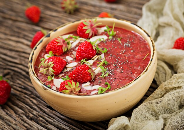 Desintoxicación y súper alimentos saludables desayuno en un tazón. Budín vegano de semillas de chía con fresas y almendras. Batido de fresas