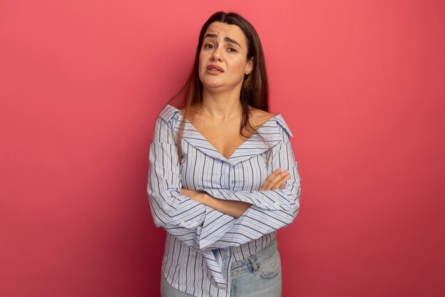 Desorientado bastante mujer caucásica se encuentra con los brazos cruzados en rosa