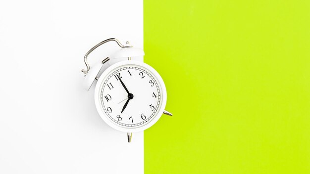 Despertador blanco sobre un fondo blanco y verde plano