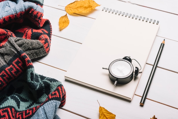 Foto gratuita despertador y efectos de escritorio cerca de bufanda y hojas de otoño