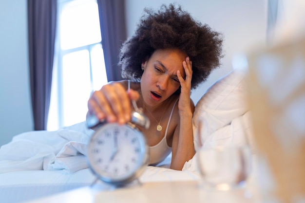 Foto gratuita despertar de una niña dormida que detiene el despertador en la cama por la mañana mujer durmiendo y despierta para apagar el despertador por la mañana