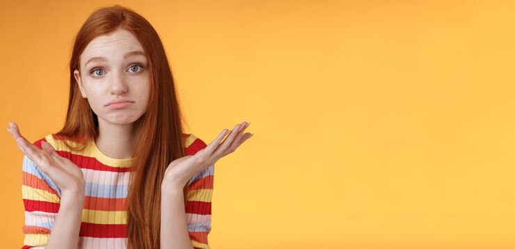 Foto gratuito despistado molesto pelirroja joven linda compañera de trabajo encogiéndose de manos extendido sideays inconsciente haciendo pucheros con