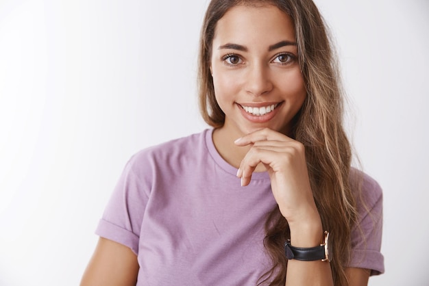 Foto gratuita despreocupada encantada feliz mujer sonriente cabello rizado con camiseta morada tocando sonriendo complacido gustando escuchar historia tener idea de plan pensando de pie pensativo satisfecho fondo blanco