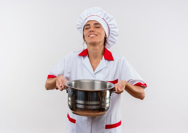 Destacó joven cocinera vistiendo uniforme de chef sosteniendo una cacerola pesada con espacio de copia