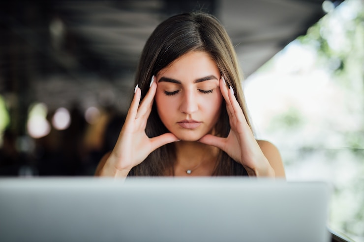 Foto gratuito destacó la ocupada joven cansada trabajando en su informe frente a la computadora portátil en el café de verano