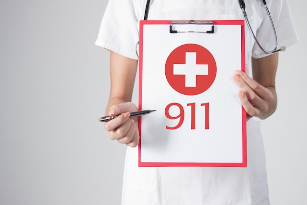 Foto gratuita detalle de un médico con estetoscopio sosteniendo un portapapeles con el icono de cruz médica. señal de llamada de emergencia. llame al 911 ambulancia. ilustración de emergencia médica. en el fondo blanco.