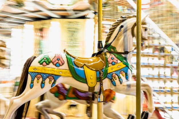 Detalle nostálgico del caballo del carrusel que gira con los desenfoques ligeros en la noche