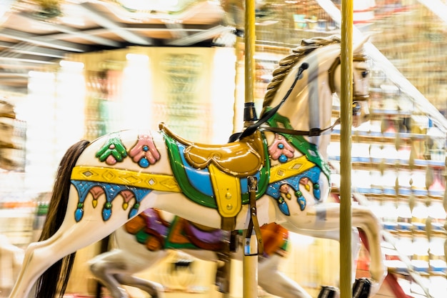 Detalle nostálgico del caballo del carrusel que gira con los desenfoques ligeros en la noche