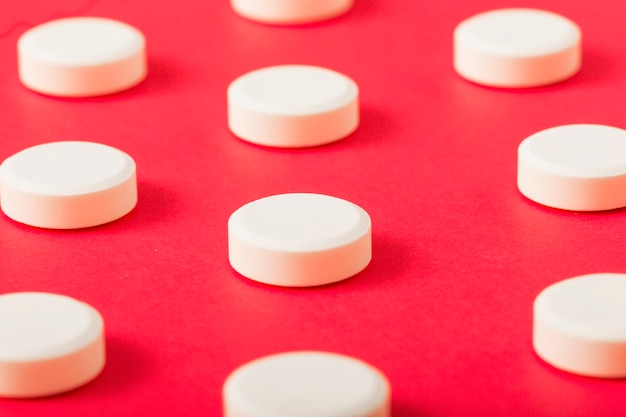 Detalle de píldoras redondas blancas sobre fondo rojo