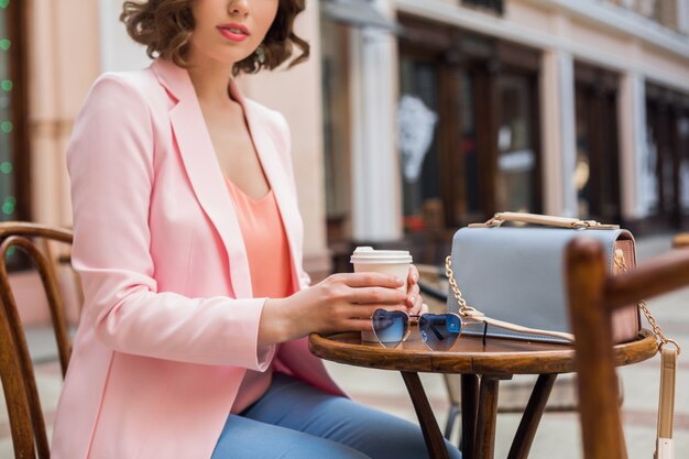 Detalles de accesorios de mujer bonita en traje elegante sentado en la cafetería, gafas de sol, bolso, colores rosa y azul, tendencia de moda primavera verano, estilo elegante, ambiente romántico, vacaciones en Europa,