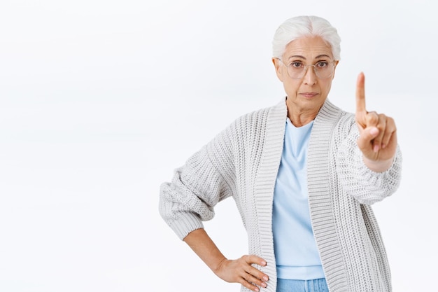 Foto gratuita detente ahí, joven. abuela estricta y disgustada de aspecto serio, anciana con cabello gris y gafas