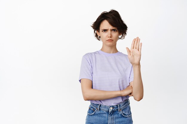 Detente, dije que no. La mujer seria y segura de sí misma levanta una mano para bloquear, desaprobar, rechazar o prohibir algo, dar advertencia, quedarse atrás, mantener la distancia, pararse en blanco.