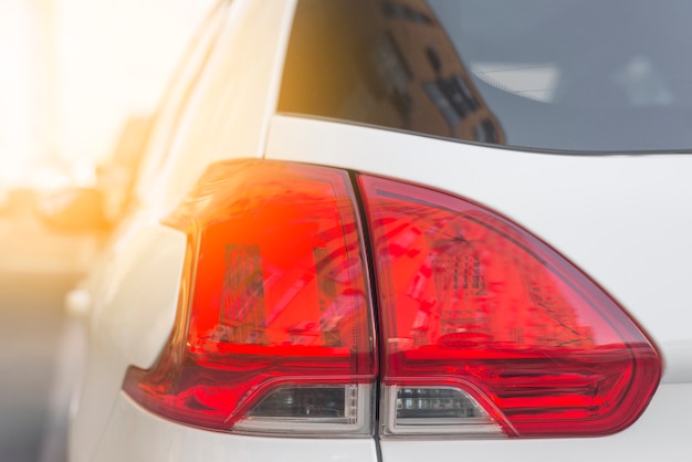 Detrás del coche blanco con luz trasera roja.