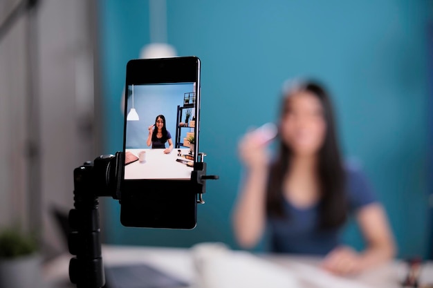 Detrás de la escena del tutorial de filmación de revisión de pincel de maquillaje de grabación de influencer de belleza con cámara de smartphone en estudio. Creador de contenido vlogging podcast cosmético para el canal de redes sociales. De cerca