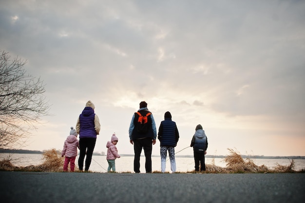 Detrás de la familia con cuatro niños en la orilla del lago