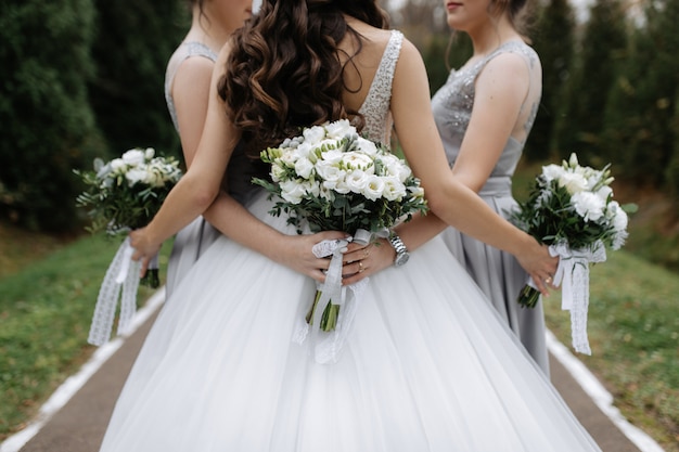 Detrás de una novia y damas de honor con ramos de boda de eustoma blanco al aire libre