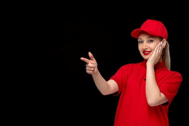 Día de la camisa roja niña sonriente tocando la cara con una gorra roja con camisa y lápiz labial brillante