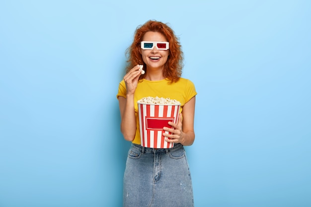 Día de cine y concepto de tiempo libre. Joven optimista pelirroja feliz se divierte mientras ve una película interesante