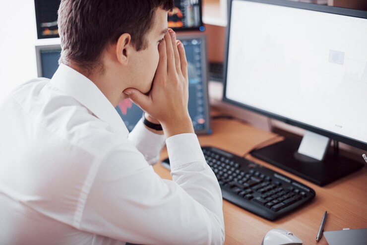 Foto gratuito día estresante en la oficina. hombre de negocios joven que lleva a cabo las manos en su cara mientras que se sienta en el escritorio en oficina creativa. concepto gráfico de la bolsa de comercio forex finanzas