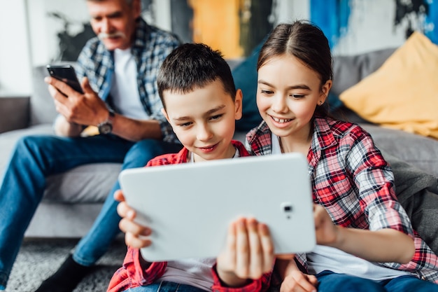 Día gracioso. Sonríe hermano y hermana hablan con la madre en la computadora portátil con su abuelo.