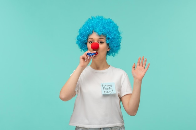 Día de los inocentes payaso chica silbato mano derecha grandes gafas de sol azules traje divertido cabello azul