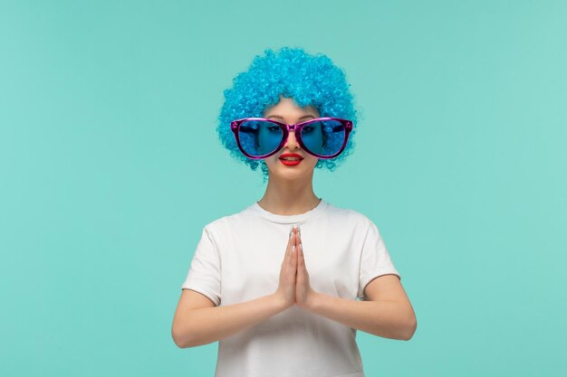 Día de los inocentes payaso orando niña manos juntas grandes gafas de sol azules traje divertido cabello azul