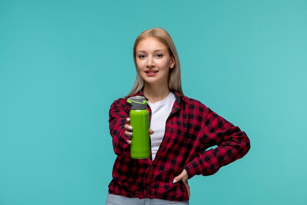 Día internacional de los estudiantes feliz niña bonita rubia en camisa roja a cuadros sosteniendo un matraz verde