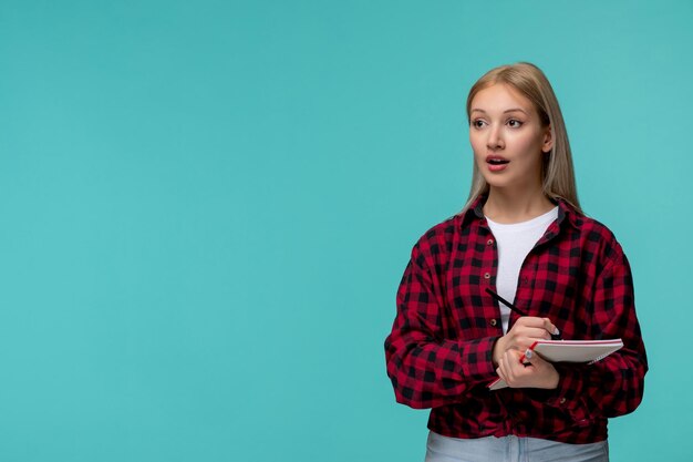 Día internacional de los estudiantes joven linda chica en camisa roja a cuadros con la boca abierta sosteniendo un lápiz