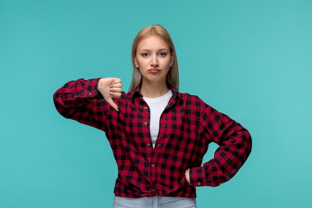 Día internacional de los estudiantes joven linda chica en camisa roja a cuadros que muestra un mal gesto