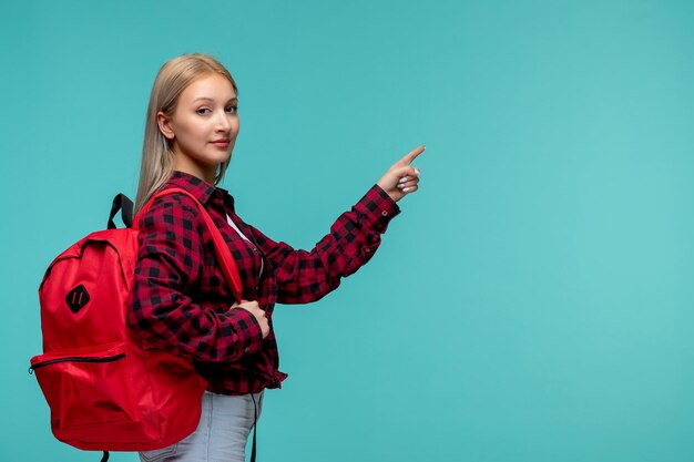 Día internacional de los estudiantes linda chica encantadora en camisa roja a cuadros con mochila roja