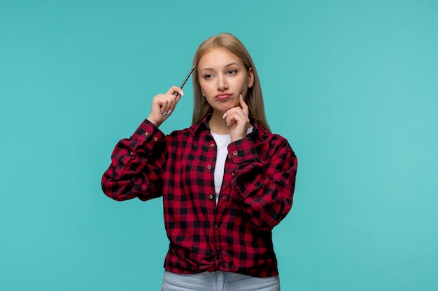 Día internacional de los estudiantes linda chica rubia con camisa roja a cuadros pensando y sosteniendo un lápiz