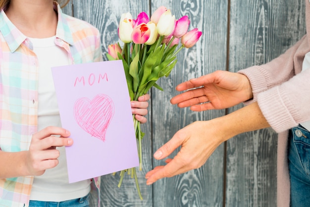 Foto gratuita día de la madre de postal y tulipanes en manos de niña.