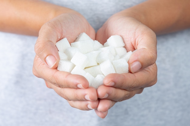 Foto gratuita día mundial de la diabetes; mano sosteniendo terrones de azúcar