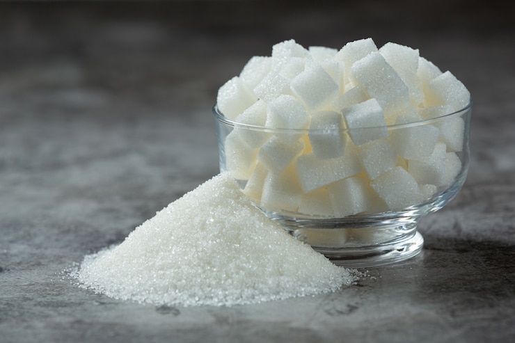 Foto gratuito día mundial de la diabetes; terrones de azúcar en un recipiente de vidrio sobre un piso oscuro