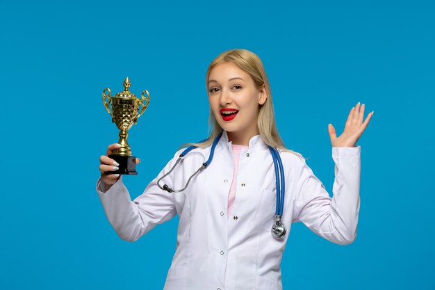 Día mundial del médico sonriente lindo doctor con trofeo dorado y el estetoscopio en la bata de laboratorio