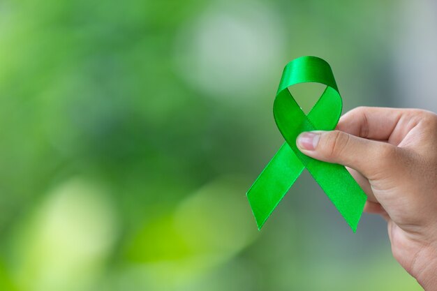 Día mundial de la salud mental. mano sosteniendo cinta verde