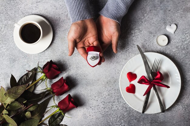 Día de San Valentín cena romántica mesa ajuste hombre mano sosteniendo el anillo de compromiso