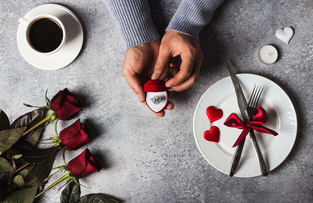 Día de San Valentín cena romántica mesa ajuste hombre mano sosteniendo el anillo de compromiso