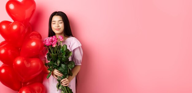 Foto gratuita día de san valentín concepto romántico adolescente niña asiática soñando con el amor o fecha cerrar los ojos y sonreír aguantando