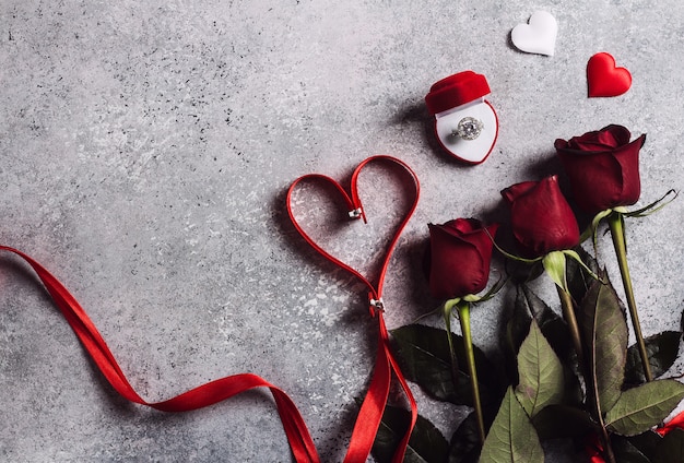 Día de San Valentín contraer matrimonio con un anillo de compromiso de boda en una caja con un ramo de rosas rojas y un corazón de cinta