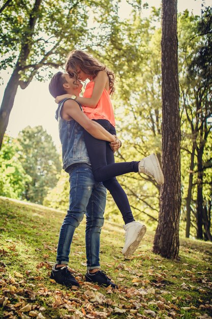 Día de San Valentín. Pareja joven informal. Un hombre que sostiene a una niña en sus brazos en el parque de primavera.