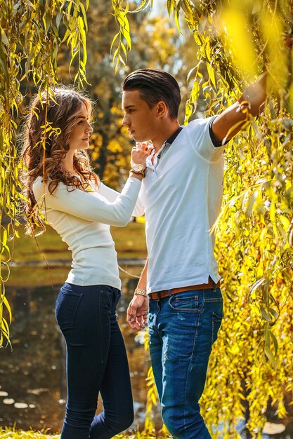 Día de San Valentín. Pareja joven posando bajo un árbol verde-amarillo.