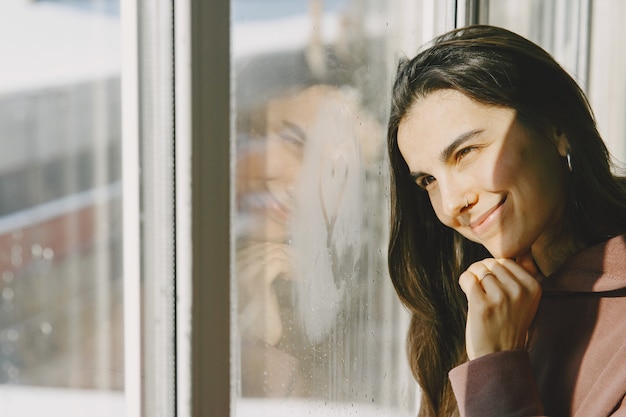 Foto gratuita día soleado. mujer llok en la ventana. ropa calida