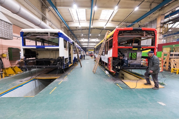 Un día de trabajo de fabricación de autobuses automáticos modernos con trabajadores de automóviles sin terminar con antecedentes de piezas de automóviles uniformes de protección